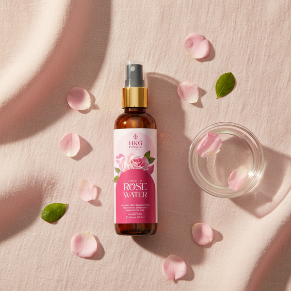 Rose Water flat lay with petals on blush linen